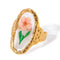 Bague en or présentant un motif de fleur rose sous verre ou résine transparente.