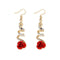 Boucles d’oreilles pendantes en spirale de couleur dorée avec des accents de cristal et des détails de roses rouges.