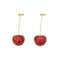 Deux cerises rouges mûres avec des tiges dorées.