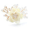 Délicate broche fleur ivoire ornée de perles et de gerbes de cristal sur des branches dorées.