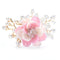 Délicate broche florale rose avec des perles et des accents de cristal sur des branches dorées.