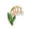 Broche décorative en forme de muguet avec des gouttes de perles et des feuilles émaillées vertes.