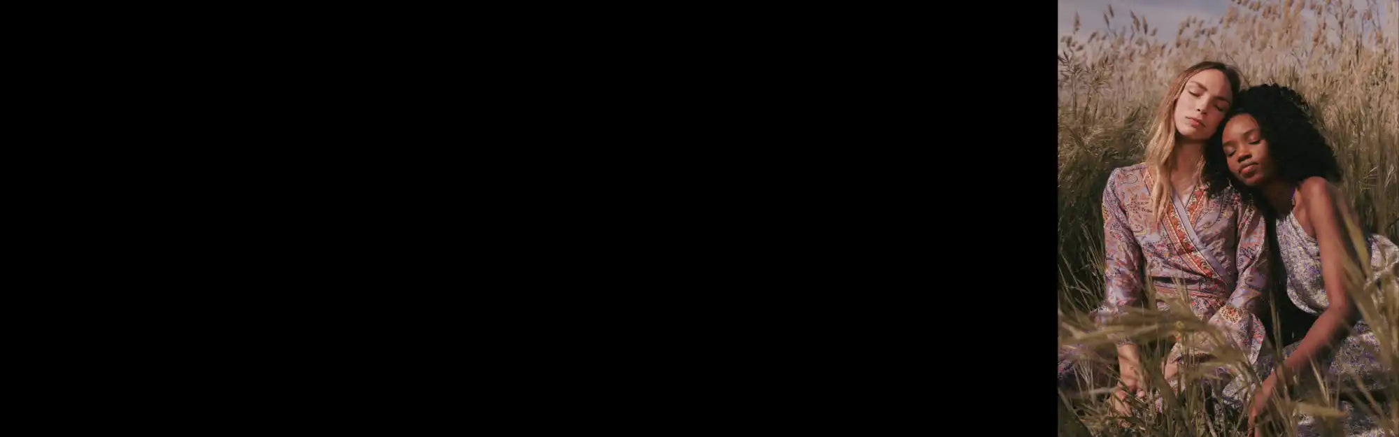 Deux amis assis côte à côte dans une haute herbe, partageant un moment tendre.