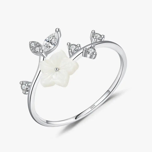Délicate bague en argent ornée d’une fleur en nacre blanche et de feuilles serties de cristaux.