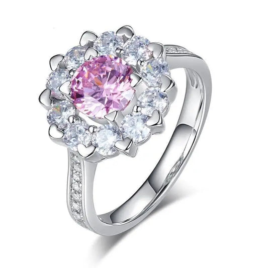 Bague en argent avec une pierre centrale rose et un halo de pierres blanches.