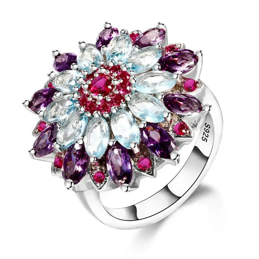 Bague en argent à motif floral, avec des pierres précieuses topaze bleue, améthyste et rubis disposées en pétales.