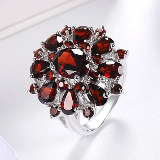 Bague en argent de forme florale avec des grenats rouge foncé disposés en grappe.