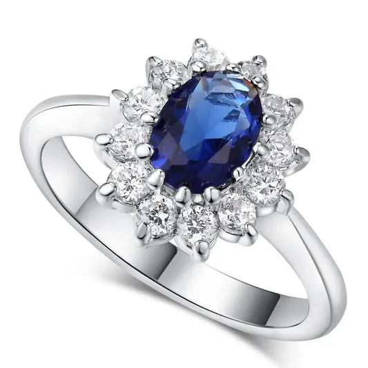 Bague en argent ornée d’un saphir bleu ovale entouré de diamants blancs.