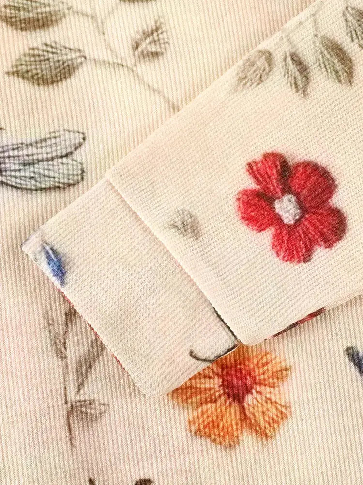 Délicates fleurs brodées avec des pétales rouges et orange sur un tissu de couleur crème.