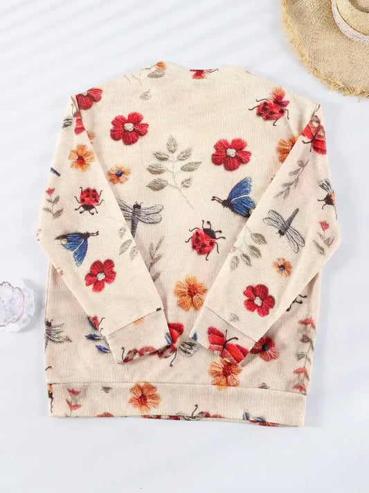 Pull-over crème imprimé de fleurs rouges, de papillons bleus et de feuilles grises.