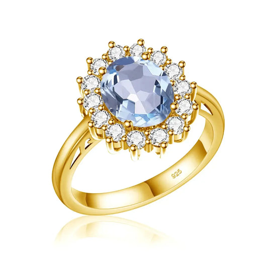 Bague en argent sterling plaqué or ornée d’une pierre précieuse bleu clair entourée de cristaux clairs dans un halo floral.