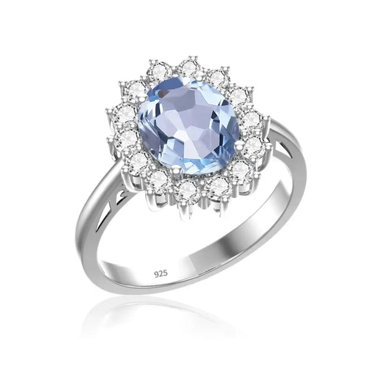 Bague en argent sterling ornée d’une pierre précieuse bleu clair entourée de cristaux blancs dans un halo floral.